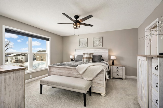 carpeted bedroom with ceiling fan and a textured ceiling