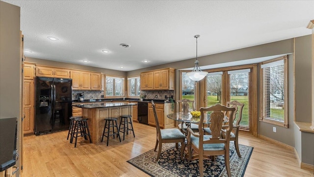 dining space with visible vents, a textured ceiling, light wood-style flooring, and baseboards