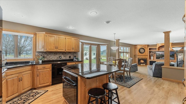 kitchen with a center island, dark countertops, open floor plan, black appliances, and a kitchen bar