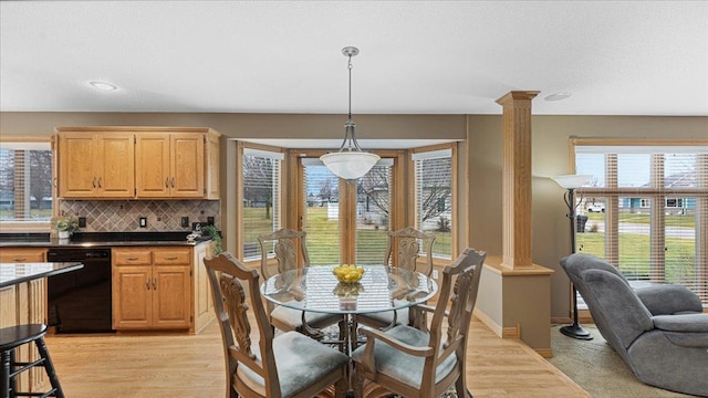 dining space featuring baseboards, a textured ceiling, light wood-type flooring, and ornate columns