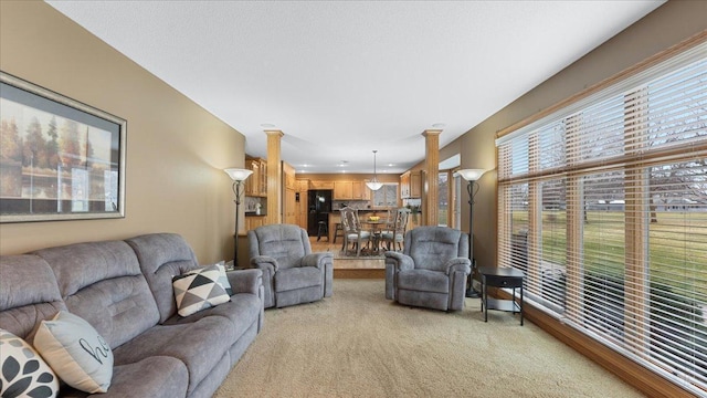 living area featuring decorative columns and light colored carpet