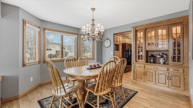 dining area featuring light wood-style flooring, baseboards, and an inviting chandelier