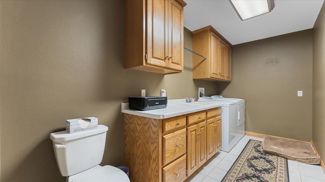 clothes washing area featuring light tile patterned floors, baseboards, washer and dryer, and laundry area