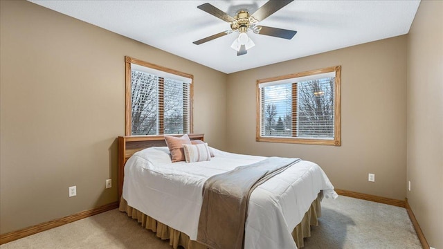bedroom with baseboards, multiple windows, and light colored carpet