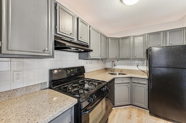 kitchen featuring gray cabinetry, light hardwood / wood-style flooring, black appliances, sink, and decorative backsplash