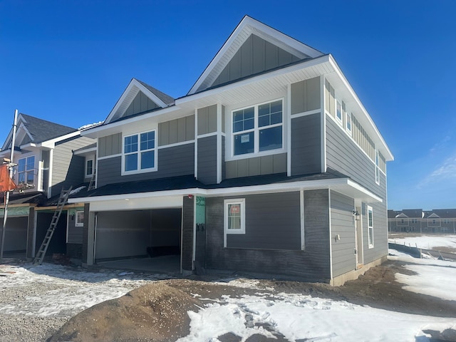 view of front of home with a garage, brick siding, and board and batten siding