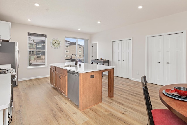 kitchen with a center island with sink, light hardwood / wood-style flooring, stainless steel appliances, and sink