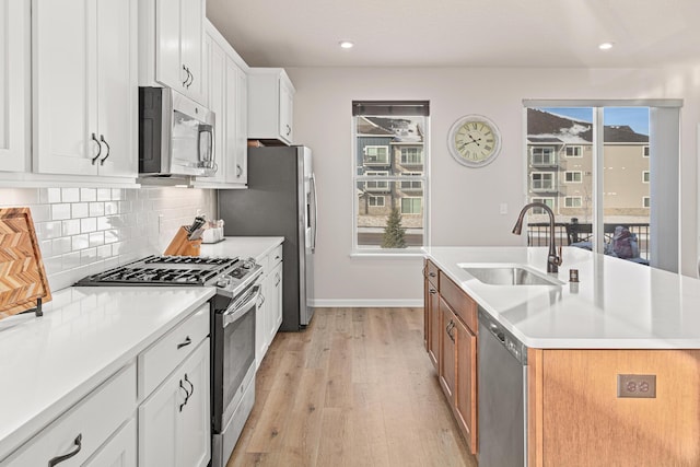 kitchen with a center island with sink, tasteful backsplash, stainless steel appliances, white cabinets, and sink