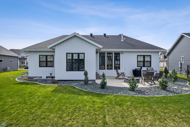 rear view of house featuring board and batten siding, a patio, a shingled roof, and a yard