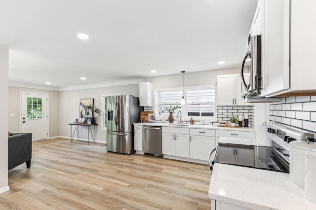 kitchen with sink, white cabinetry, pendant lighting, stainless steel appliances, and tasteful backsplash