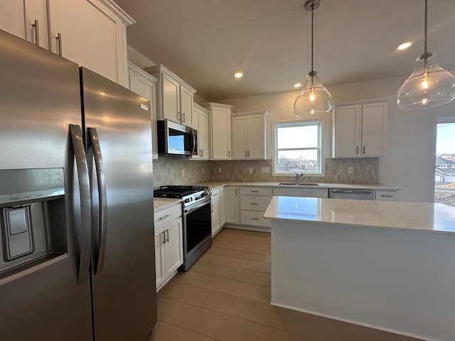 kitchen featuring stainless steel appliances, light countertops, and white cabinetry