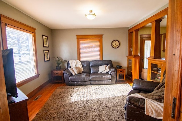 living room with decorative columns and dark hardwood / wood-style floors