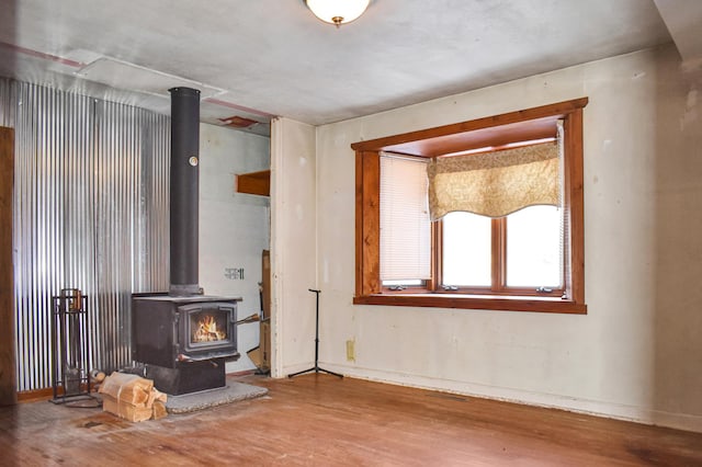 unfurnished living room featuring baseboards, a wood stove, and wood finished floors