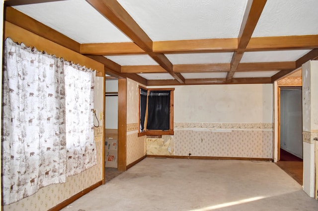 empty room with wallpapered walls, coffered ceiling, wainscoting, and beamed ceiling