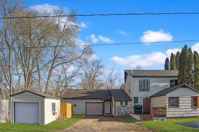 view of front of property with a front lawn, a deck, dirt driveway, a shingled roof, and an outbuilding