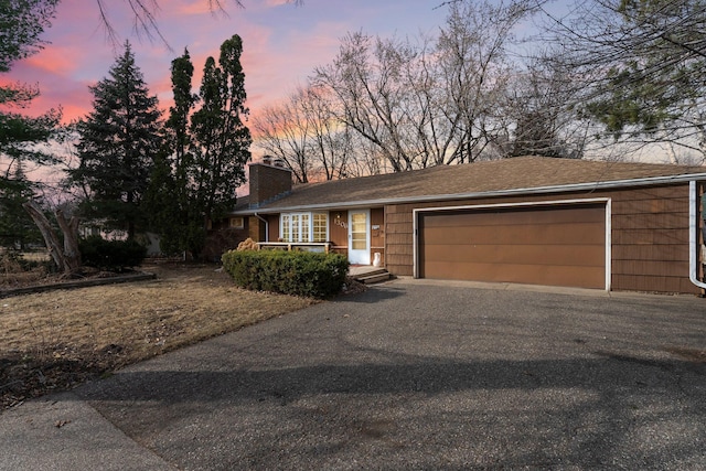 view of front of home featuring aphalt driveway, an attached garage, and a chimney