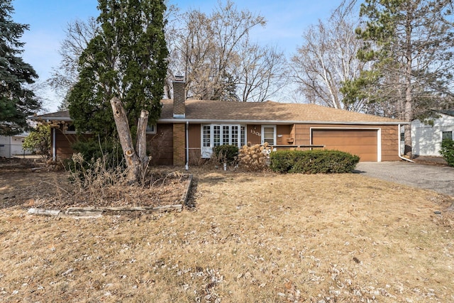 single story home with a garage, a chimney, and driveway