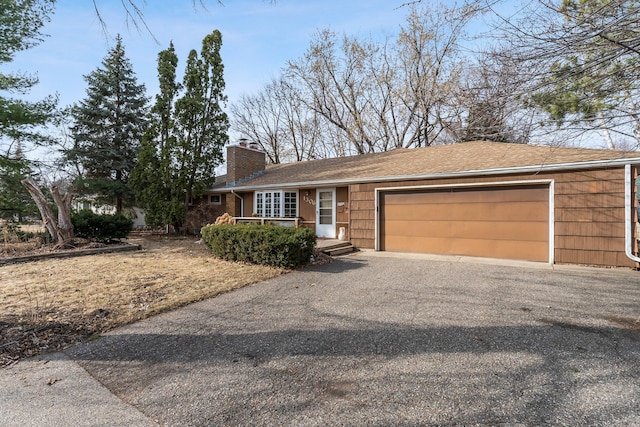 ranch-style house featuring driveway, a chimney, and an attached garage