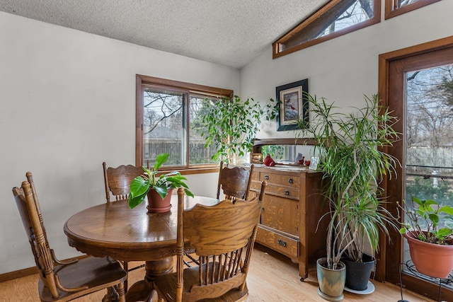 dining room featuring lofted ceiling, a textured ceiling, and light wood finished floors