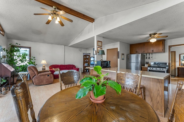 dining room with lofted ceiling with beams, light wood-type flooring, a textured ceiling, and a ceiling fan