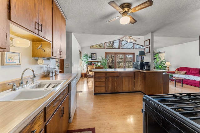 kitchen with brown cabinets, a sink, ceiling fan, light countertops, and light wood-type flooring