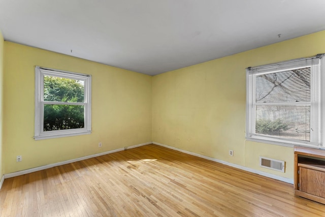 empty room featuring light wood finished floors, visible vents, and baseboards