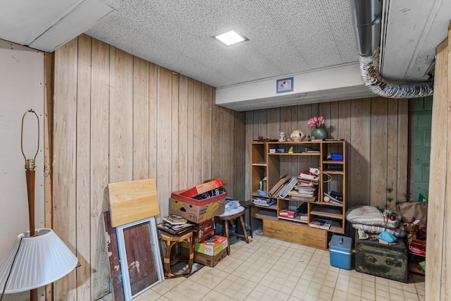 finished below grade area featuring tile patterned floors and wood walls