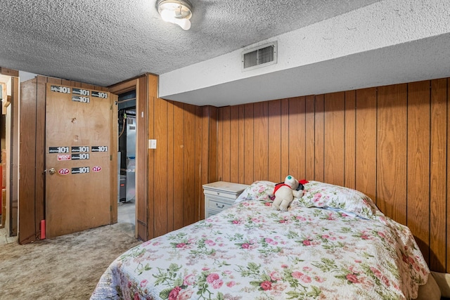 carpeted bedroom featuring visible vents, wooden walls, and a textured ceiling