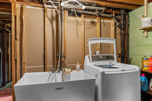 clothes washing area with a sink, concrete block wall, washer / dryer, and laundry area