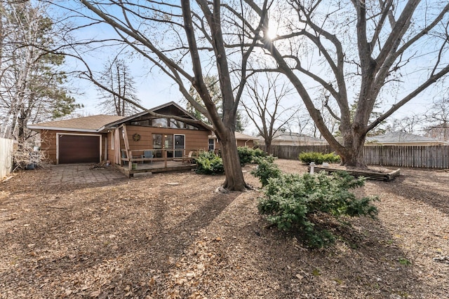 view of yard with a deck, an attached garage, and fence