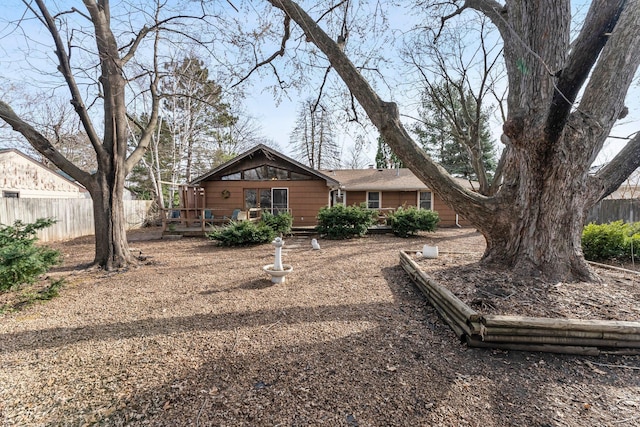 rear view of property featuring a deck and fence