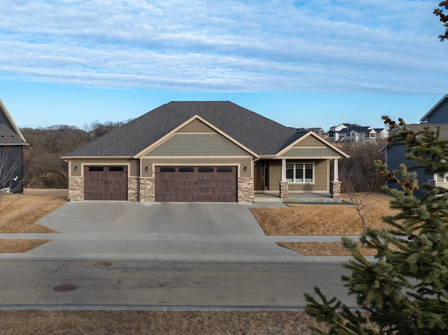 craftsman-style house featuring a garage, concrete driveway, and stone siding