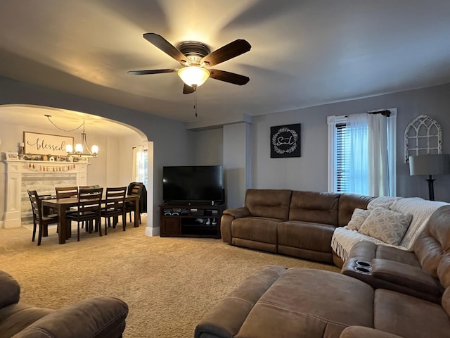 living room featuring ceiling fan with notable chandelier and light colored carpet