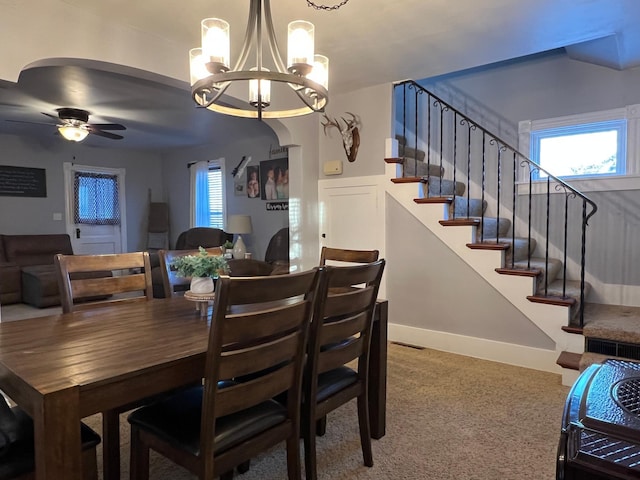 dining space featuring ceiling fan with notable chandelier