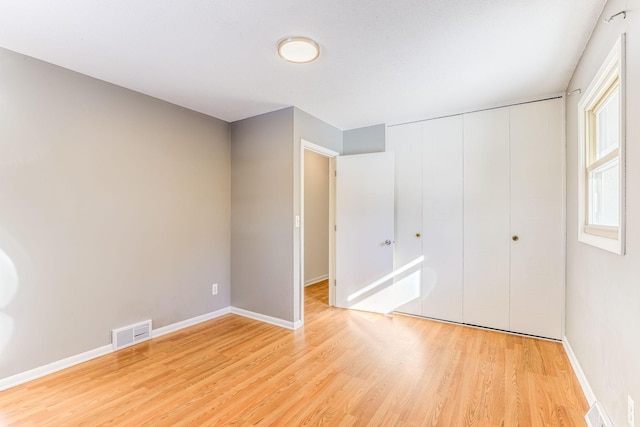 unfurnished bedroom with light wood-type flooring and a closet