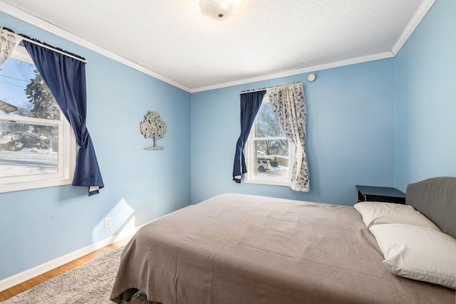 bedroom with a textured ceiling, crown molding, baseboards, and wood finished floors