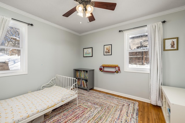 bedroom featuring crown molding, light wood-style floors, baseboards, and ceiling fan