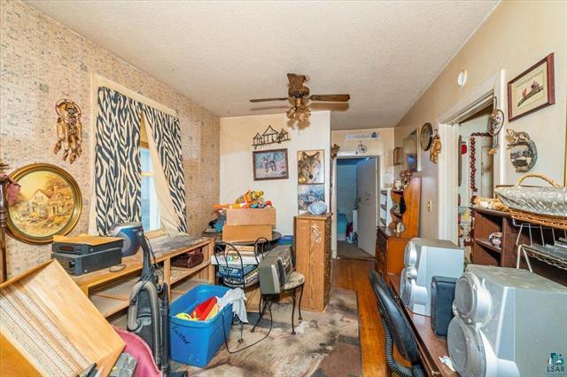 interior space with ceiling fan, wood-type flooring, and a textured ceiling