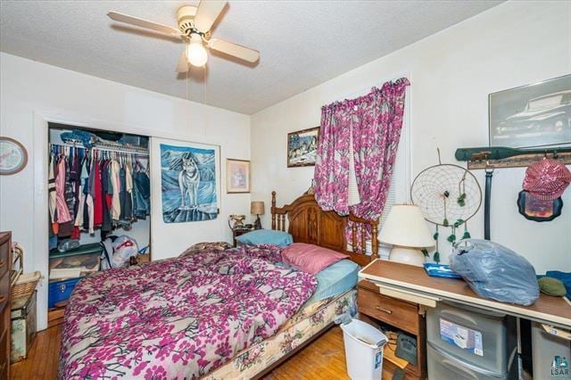 bedroom featuring ceiling fan, a closet, wood-type flooring, and a textured ceiling