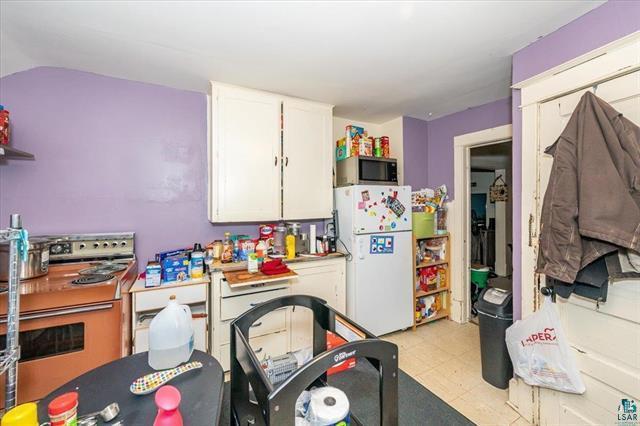 kitchen with white cabinets, white refrigerator, stove, and lofted ceiling