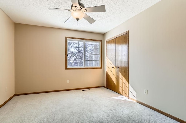 spare room featuring light carpet, a textured ceiling, visible vents, and baseboards