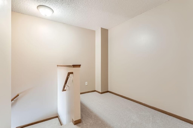 stairs with a textured ceiling, baseboards, and carpet flooring