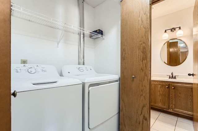 clothes washing area with laundry area, light tile patterned flooring, independent washer and dryer, and a sink