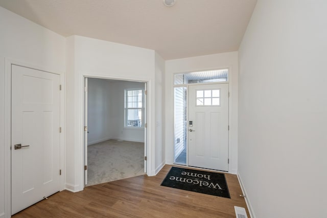 foyer entrance featuring visible vents, baseboards, and wood finished floors