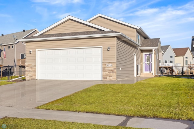 view of front facade with concrete driveway, an attached garage, a front yard, fence, and stone siding