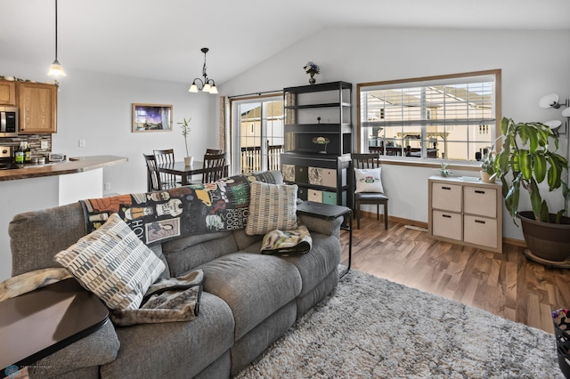 living room featuring lofted ceiling, a notable chandelier, and light wood-style flooring