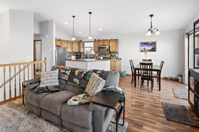 living room featuring light wood finished floors, baseboards, vaulted ceiling, a chandelier, and recessed lighting