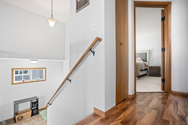 stairs with wood finished floors, a towering ceiling, and baseboards