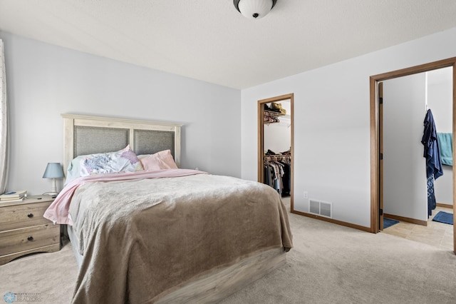 carpeted bedroom featuring baseboards, visible vents, a walk in closet, and a closet