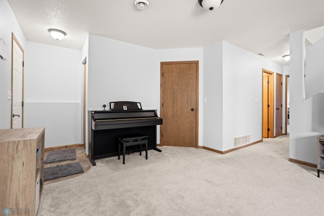 sitting room featuring a textured ceiling, carpet flooring, visible vents, and baseboards